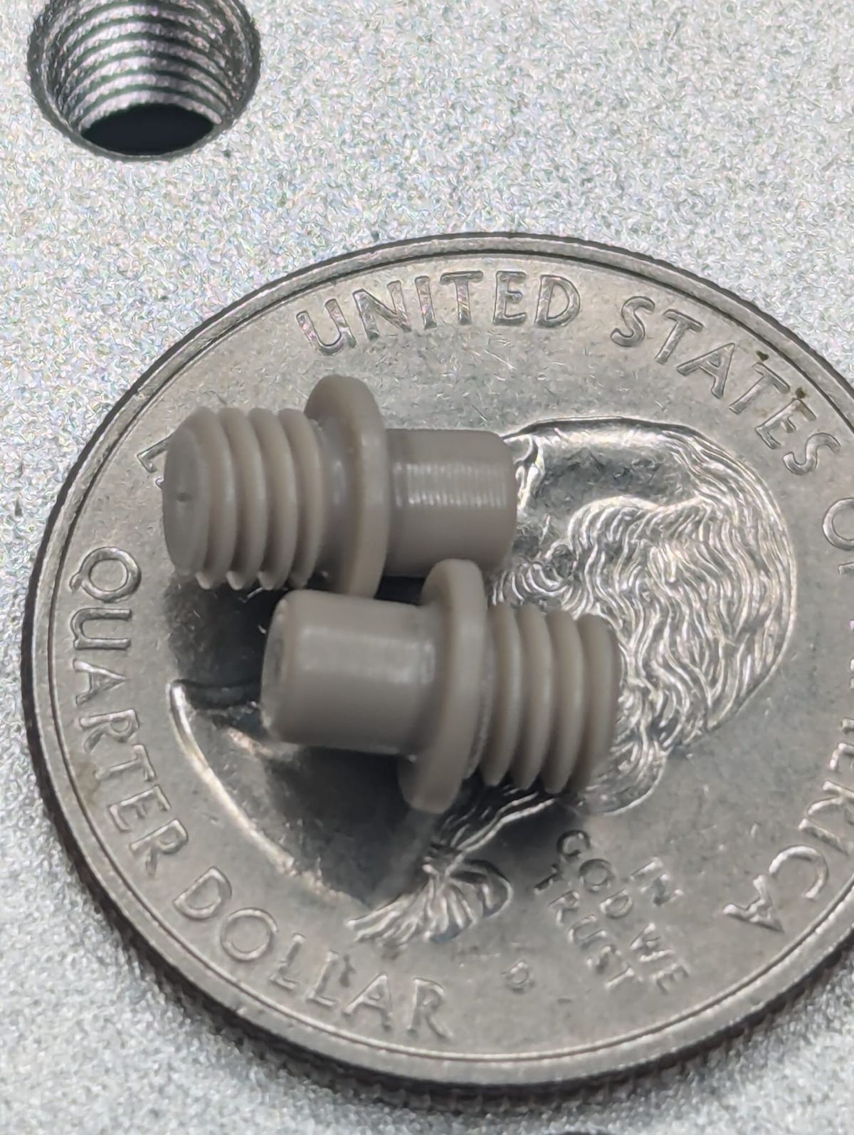 Tiny turned parts sitting on a quarter for scale